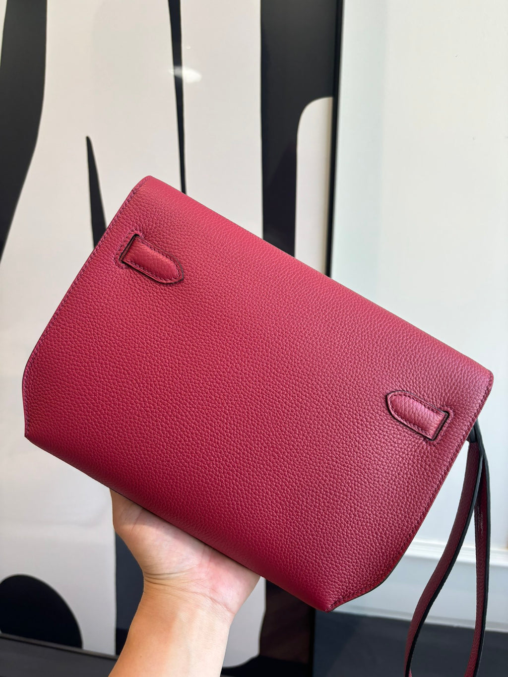Hermes bag with red textured finish, top flap, and small front pocket detail.
