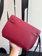 Hermes bag with red textured finish, top flap, and small front pocket detail.