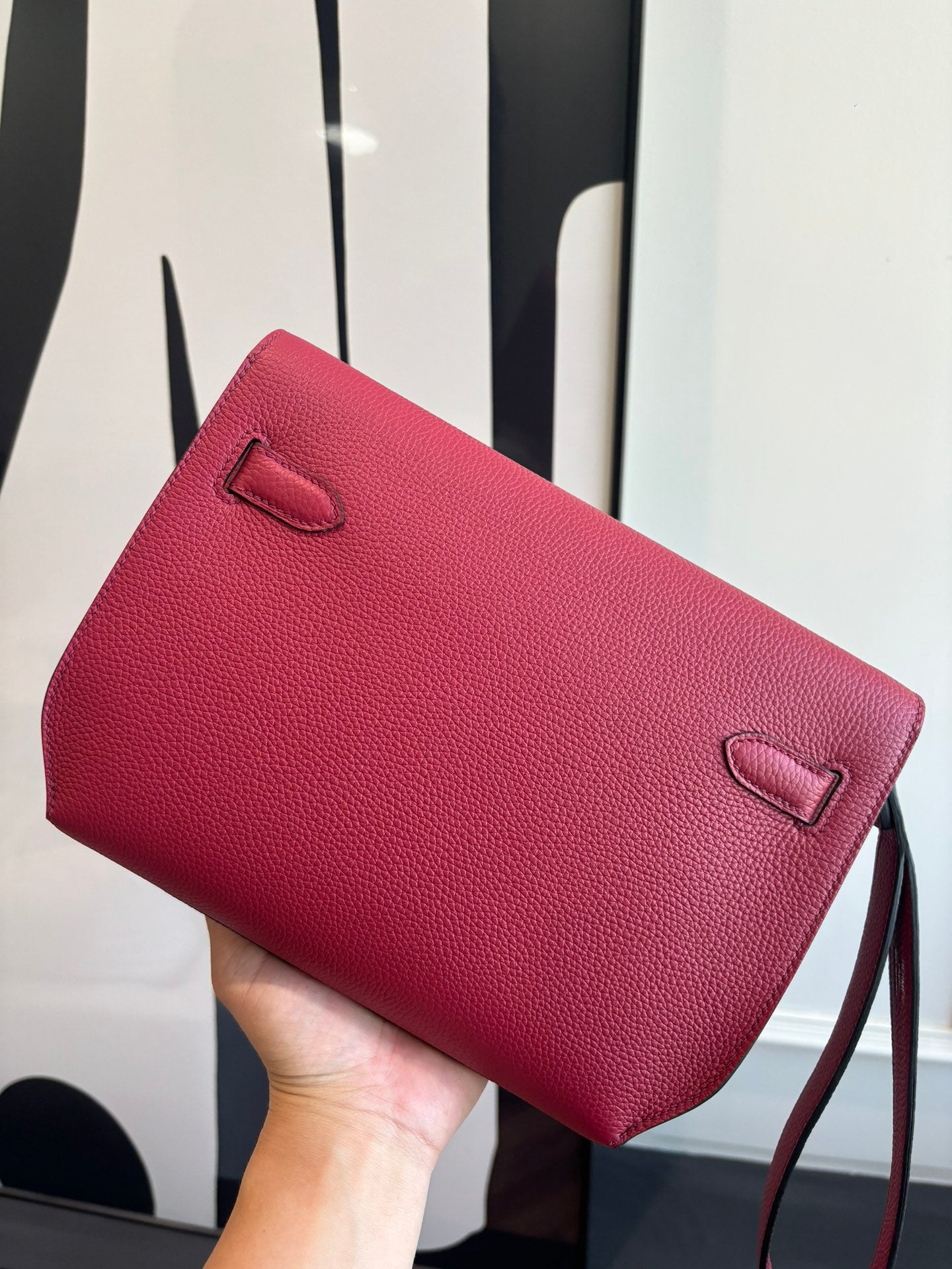 Hermes bag with red textured finish, top flap, and small front pocket detail.