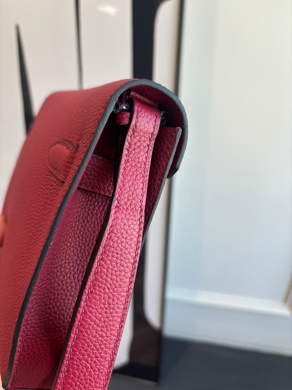 Hermes bag side view with structured red leather, open top, and interior compartment.