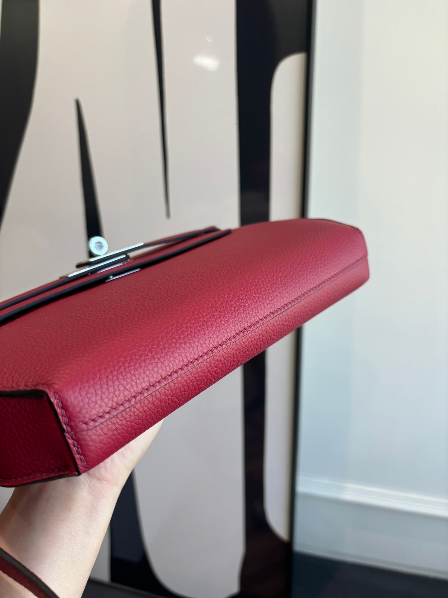 Hermes bag underside view with red textured leather and top flap clasp.