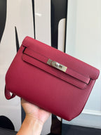 Hermes bag in textured red leather with front flap and silver-toned buckle clasp.