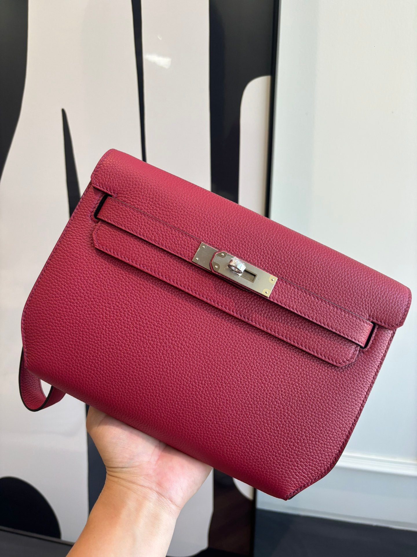 Hermes bag in textured red leather with front flap and silver-toned buckle clasp.