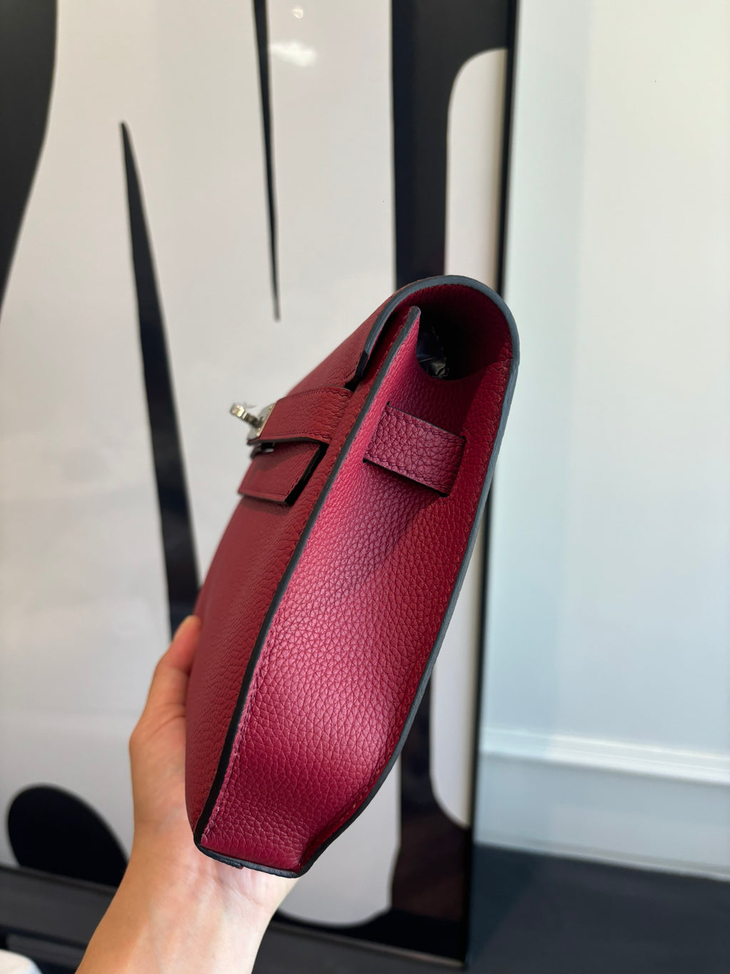 Hermes bag standing upright with top handle, red leather exterior, and interior lining.