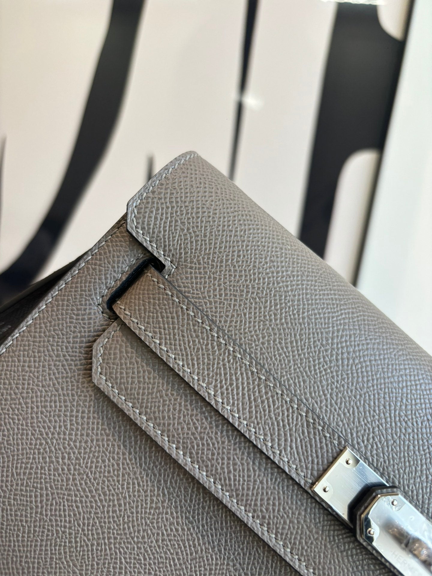 Gray pebbled leather clutch bag close-up of front flap and metal clasp