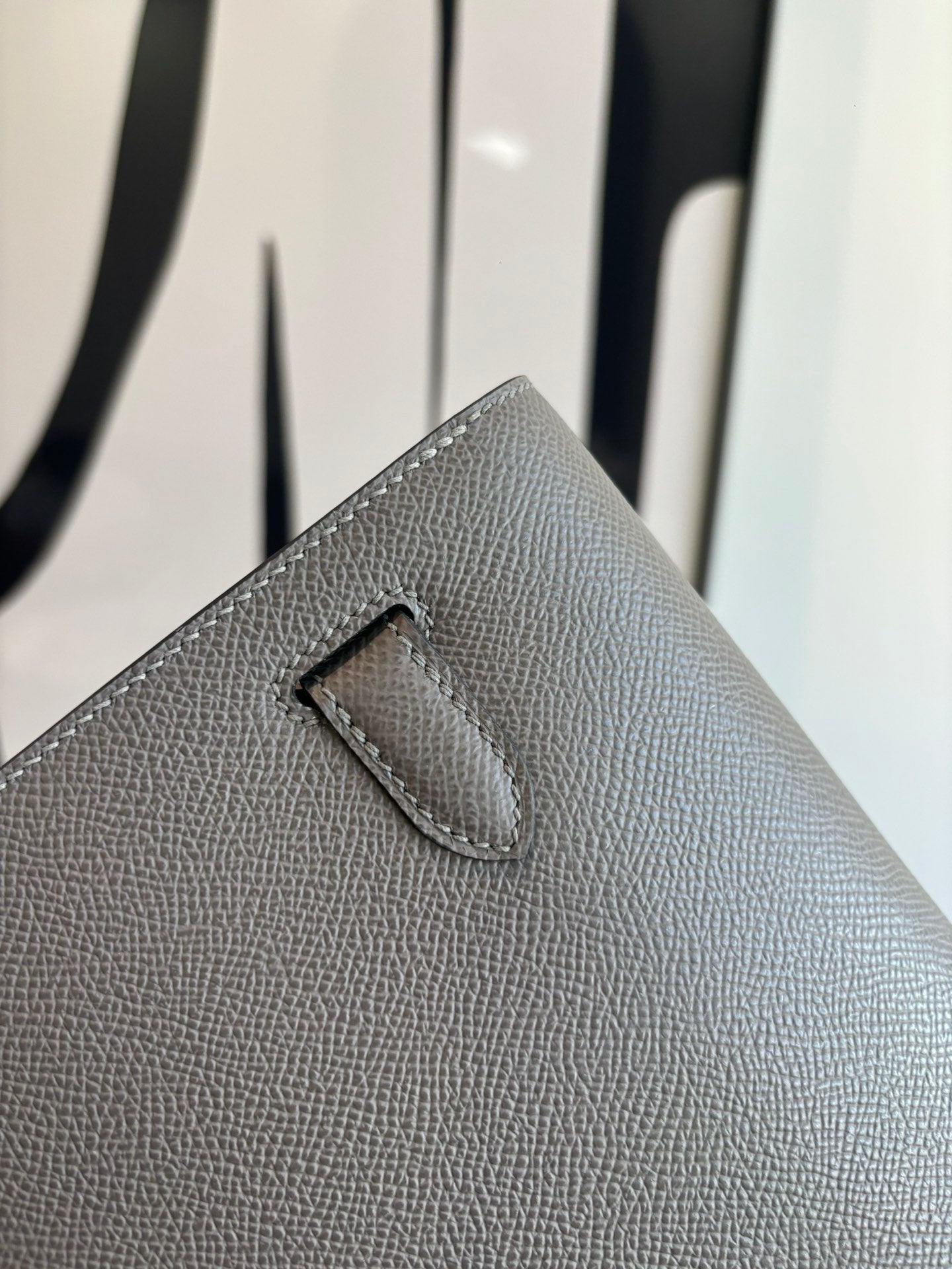 Gray pebbled leather clutch bag front flap with stitched center tab detail