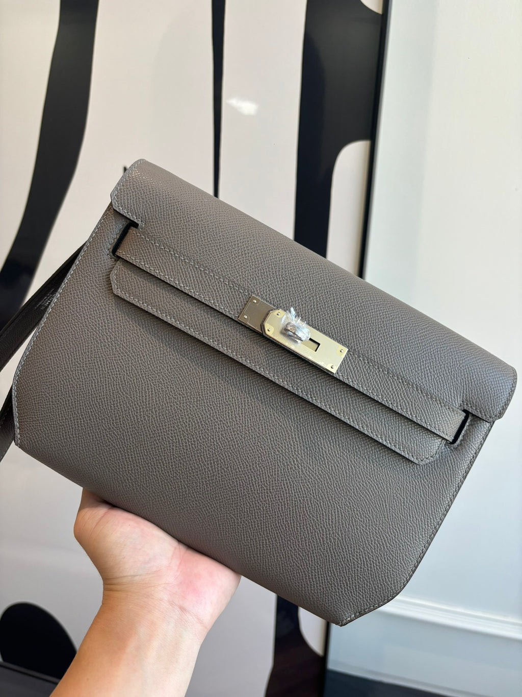 Gray pebbled leather clutch bag with front flap and turn-lock clasp