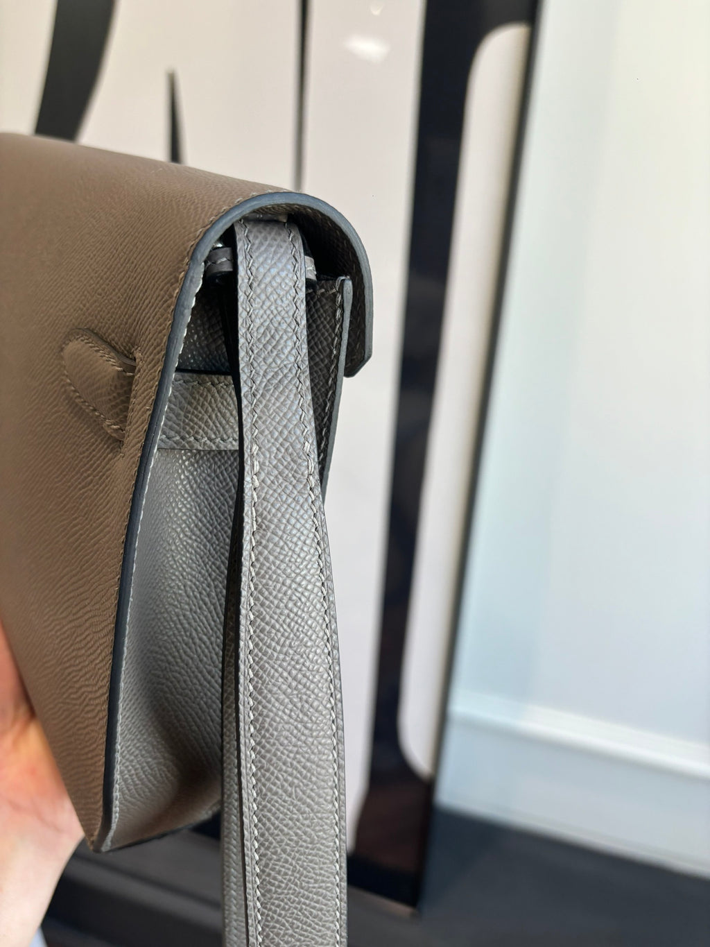 Gray leather clutch bag interior view with long strap and top opening