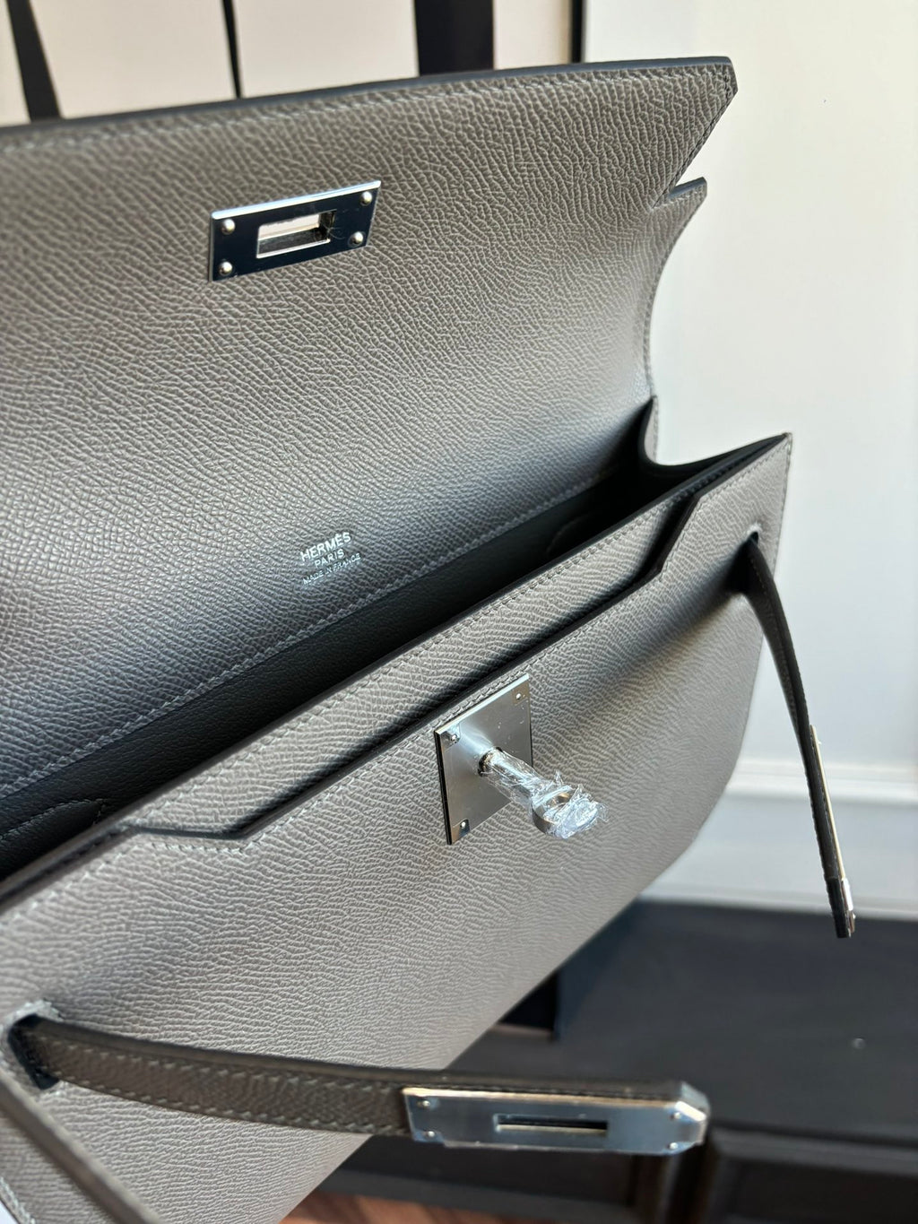 Gray pebbled leather clutch bag with hinged front clasp and inner opening