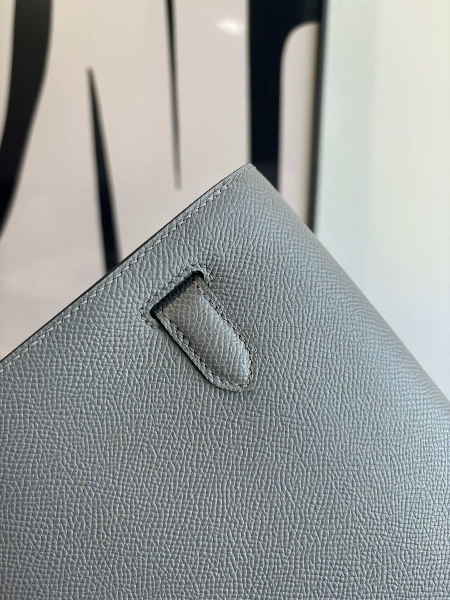 Hermes bag close-up of front flap tab on light blue-gray textured leather