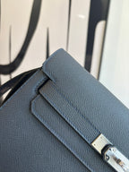 Hermes bag flap detail with gold hardware and pebbled blue leather