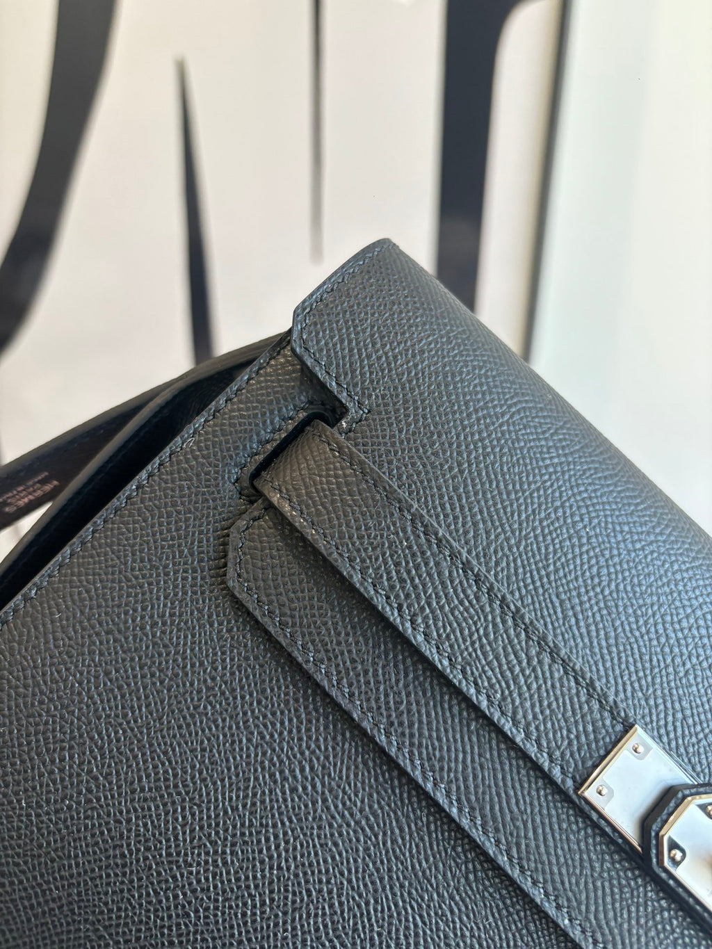Flap bag close-up: textured leather and silver turn-lock detail on dark blue front