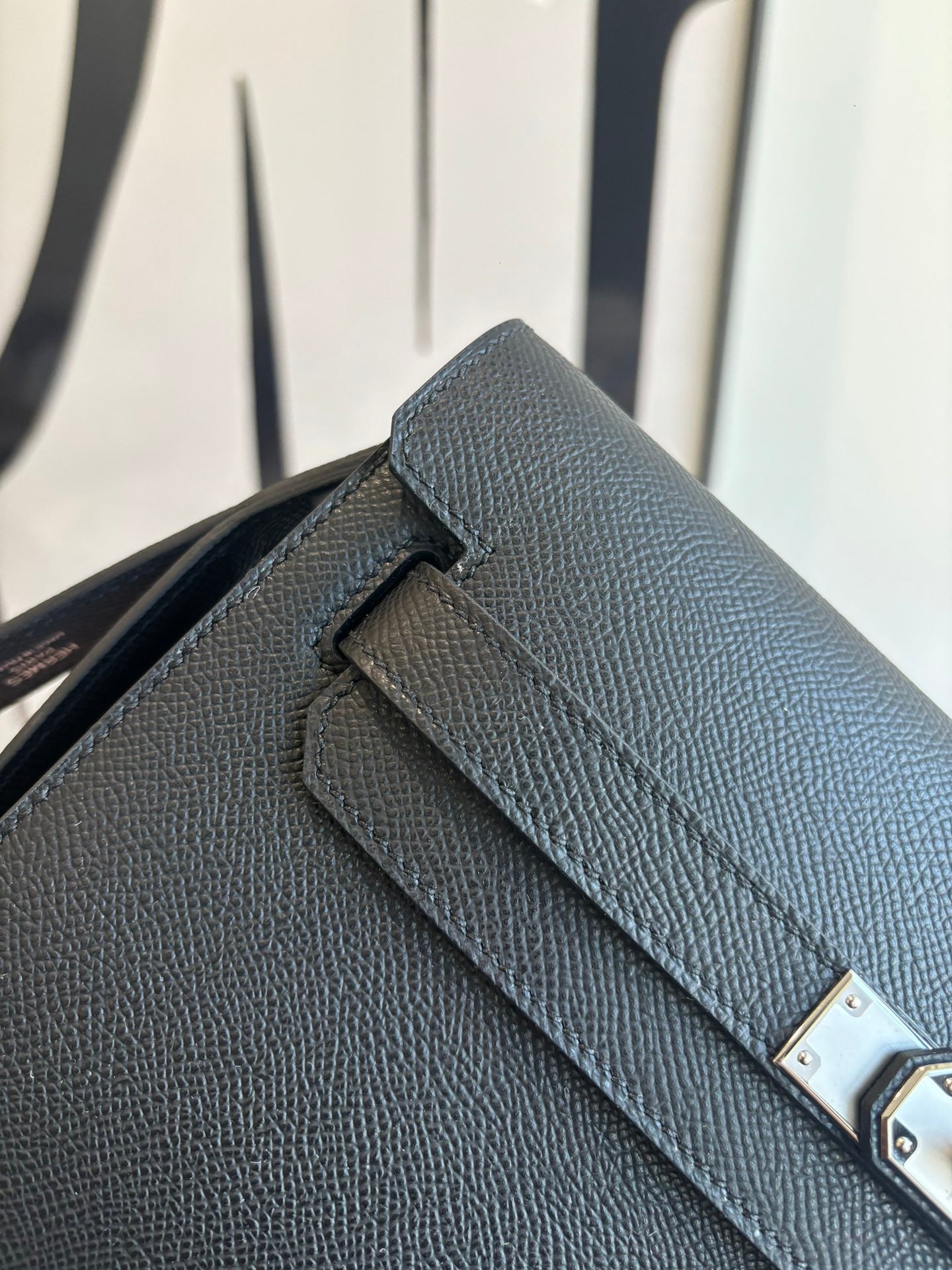 Flap bag close-up: textured leather and silver turn-lock detail on dark blue front