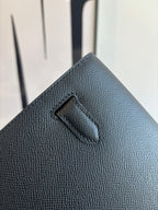 Flap bag corner close-up with stitched handle loop on textured dark blue leather