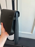Flap bag side profile with long strap and stitched edges, dark blue leather