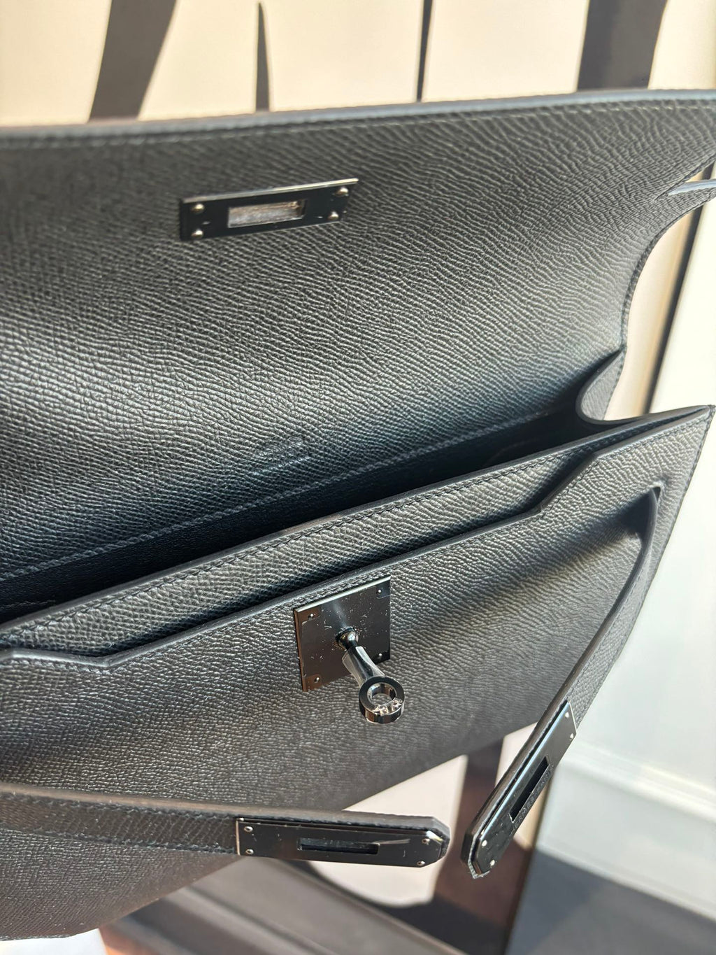 Hermes bag open clasp area close-up with textured dark leather and metal latch