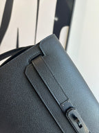 Hermes bag close-up: textured leather flap with engraved metal buckle hardware