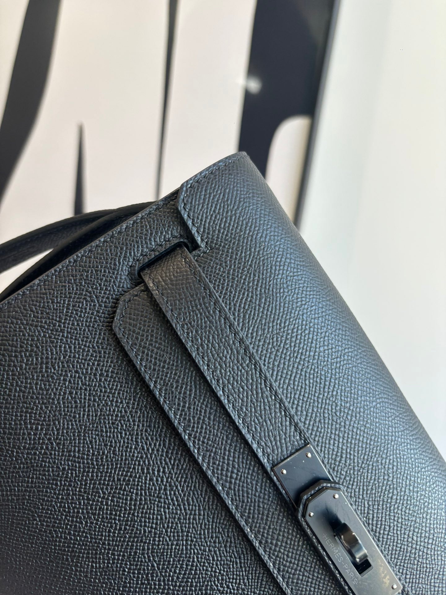 Hermes bag close-up: textured leather flap with engraved metal buckle hardware