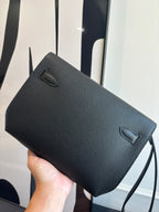 Hermes bag side view with flap closure, textured dark leather and slim strap loop