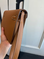 Brown leather flap bag side view with double strap and stitched edges