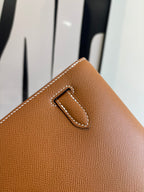 Brown leather flap bag corner detail with stitched tab and metal clasp
