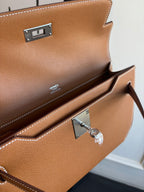 Brown leather flap bag interior view with metal lock plate and stitched compartments