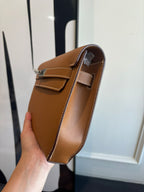 Brown leather shoulder bag with top handle, flap closure, and metal clasp