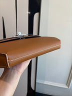 Brown leather flap bag top edge view with contrast piping and short strap