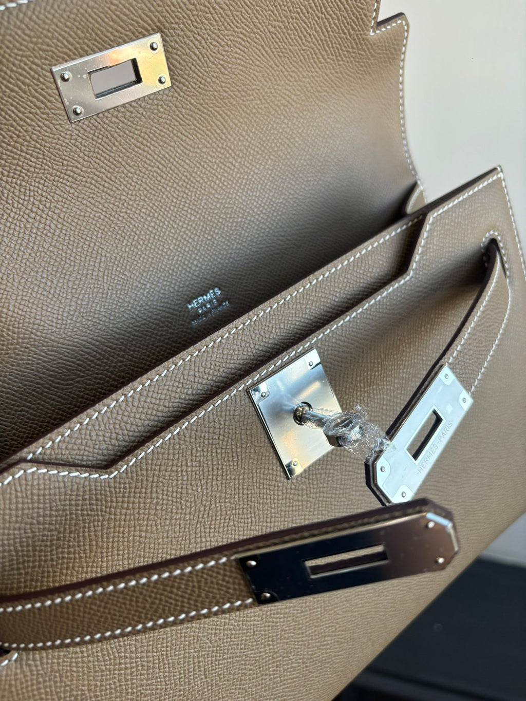 Hermes flap shoulder bag clasp close-up with silver hardware and stitched trim