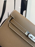 Hermes flap shoulder bag detail: silver-tone buckle and white edge stitching