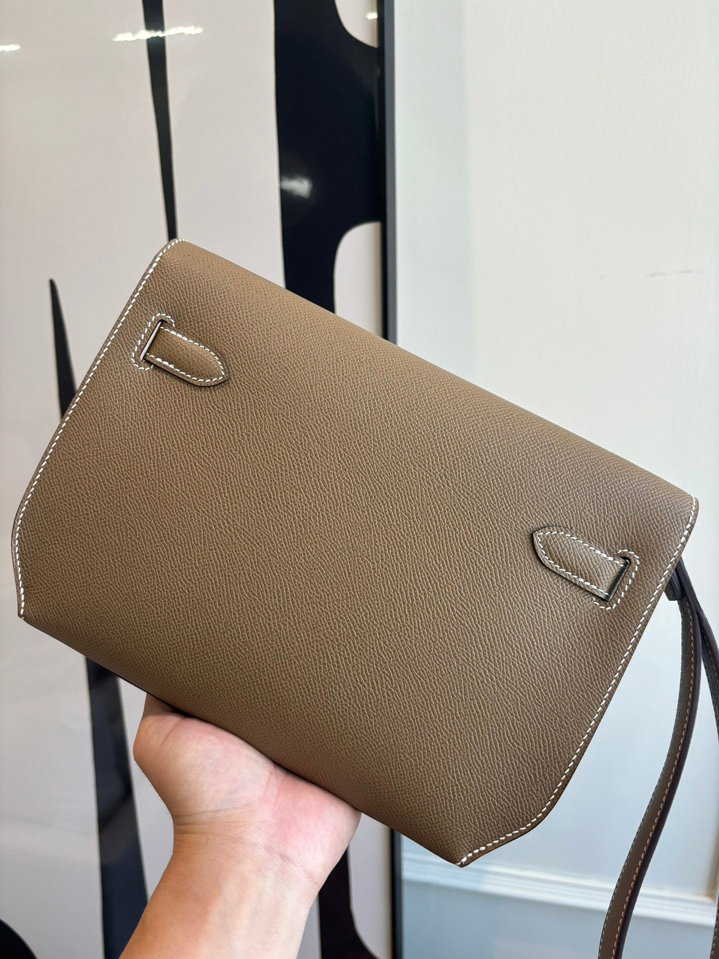 Hermes flap shoulder bag front view with dual buckle accents in brown leather