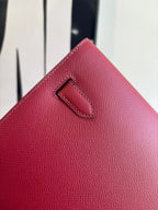 Red textured leather bag with front flap tab and stitched edge
