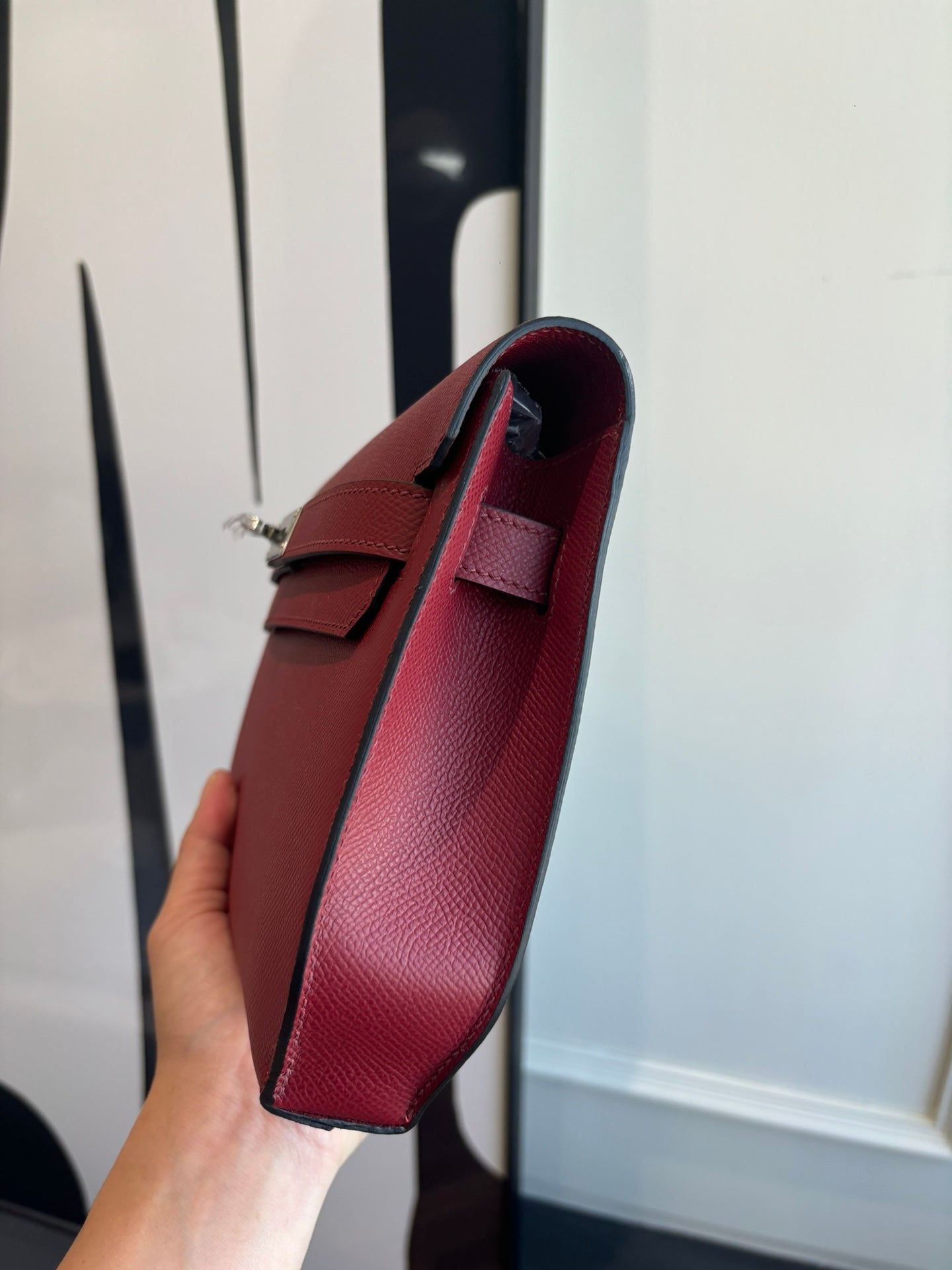 Red leather shoulder bag with top handle and long strap, side view