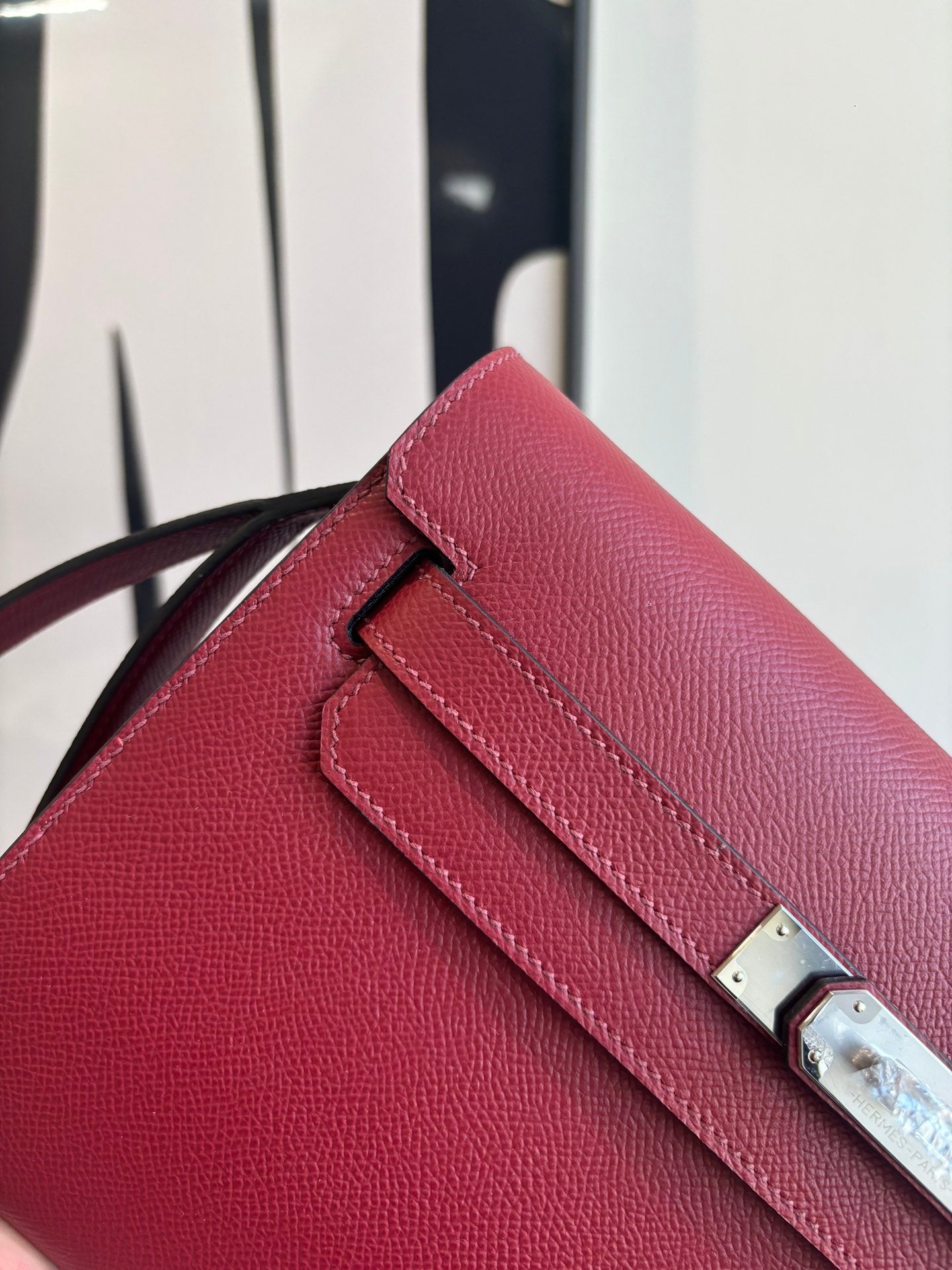 Red leather bag flap detail with silver-tone turn-lock and stitched strap