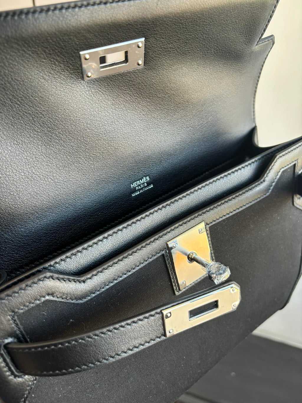 Hermes bag interior view with fabric lining, logo label, and gold-tone clasp detail