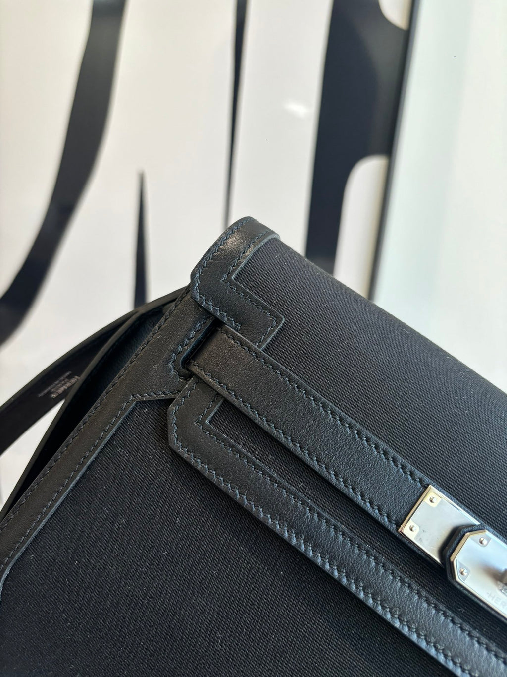 Hermes bag close-up of front flap, stitched edging, and rectangular gold-tone hardware