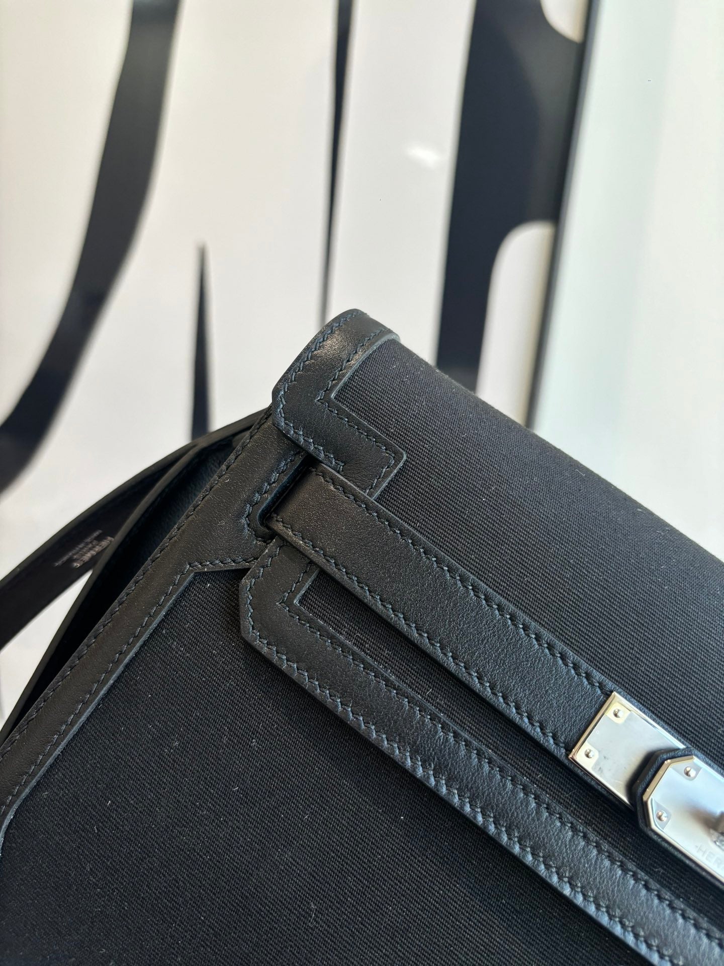 Hermes bag close-up of front flap, stitched edging, and rectangular gold-tone hardware