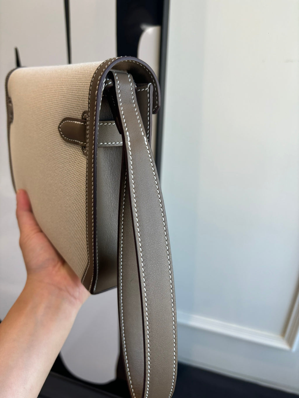 Hermes bag side view with beige body, brown trim, and long crossbody strap