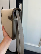 Hermes bag side view with beige body, brown trim, and long crossbody strap