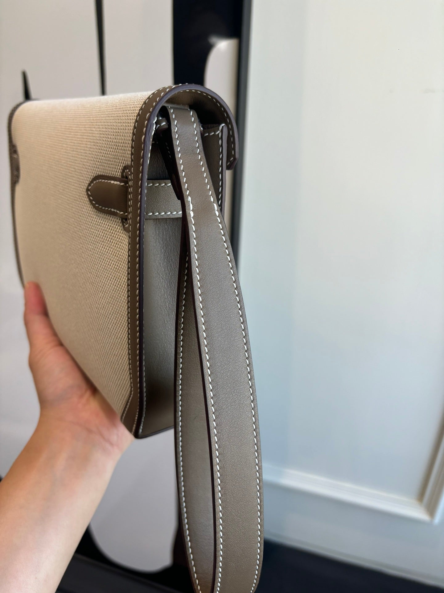 Hermes bag side view with beige body, brown trim, and long crossbody strap