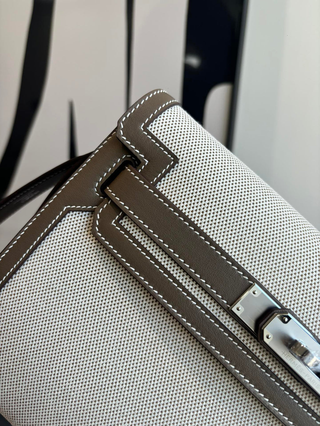 Close-up of beige textured Hermes bag front strap with buckle and stitched trim