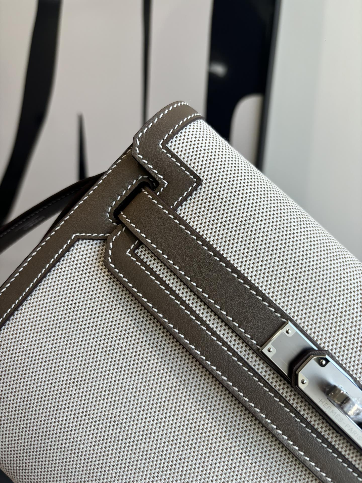 Close-up of beige textured Hermes bag front strap with buckle and stitched trim