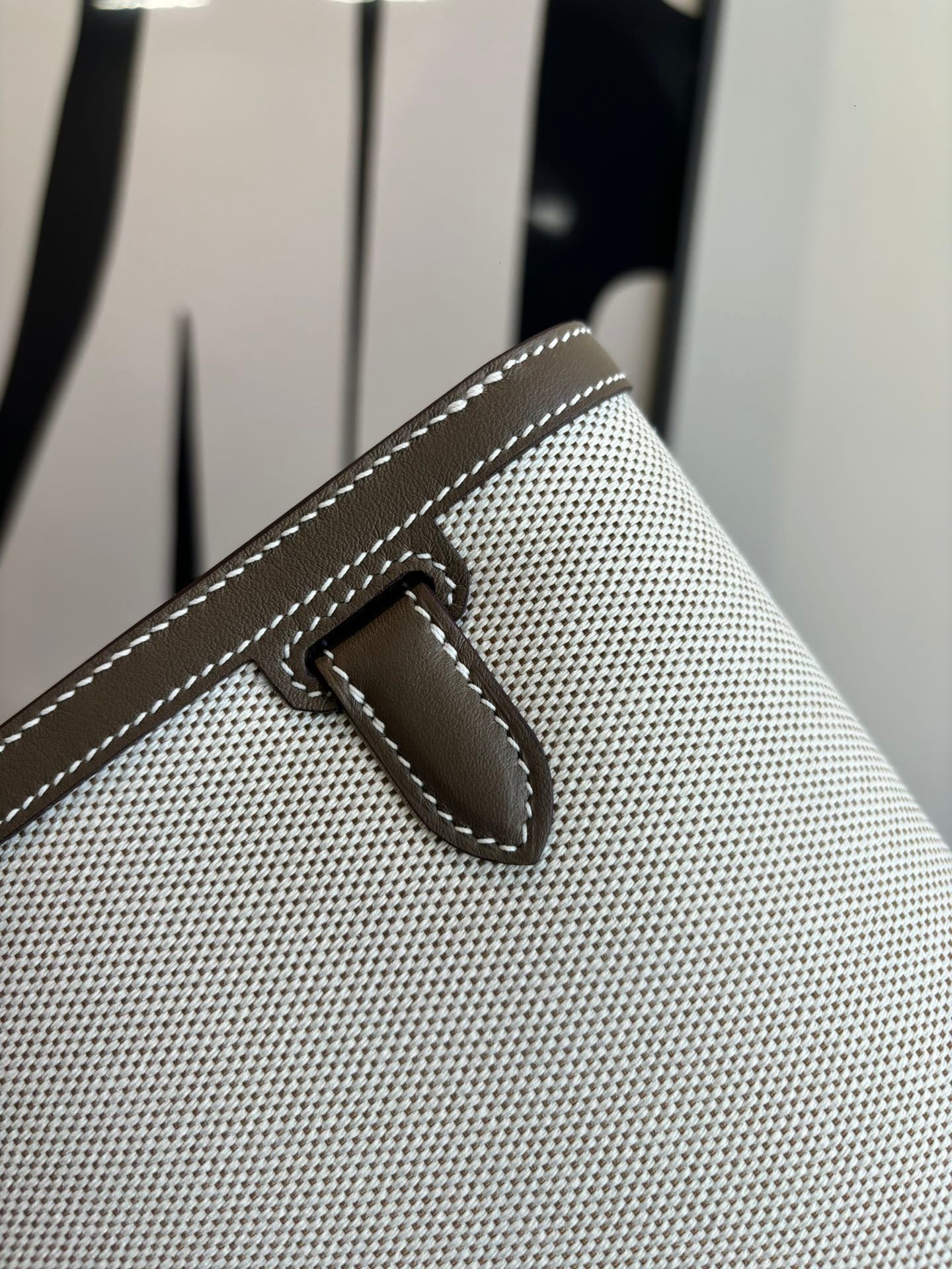 Beige textured Hermes bag front flap tab with stitched leather detail