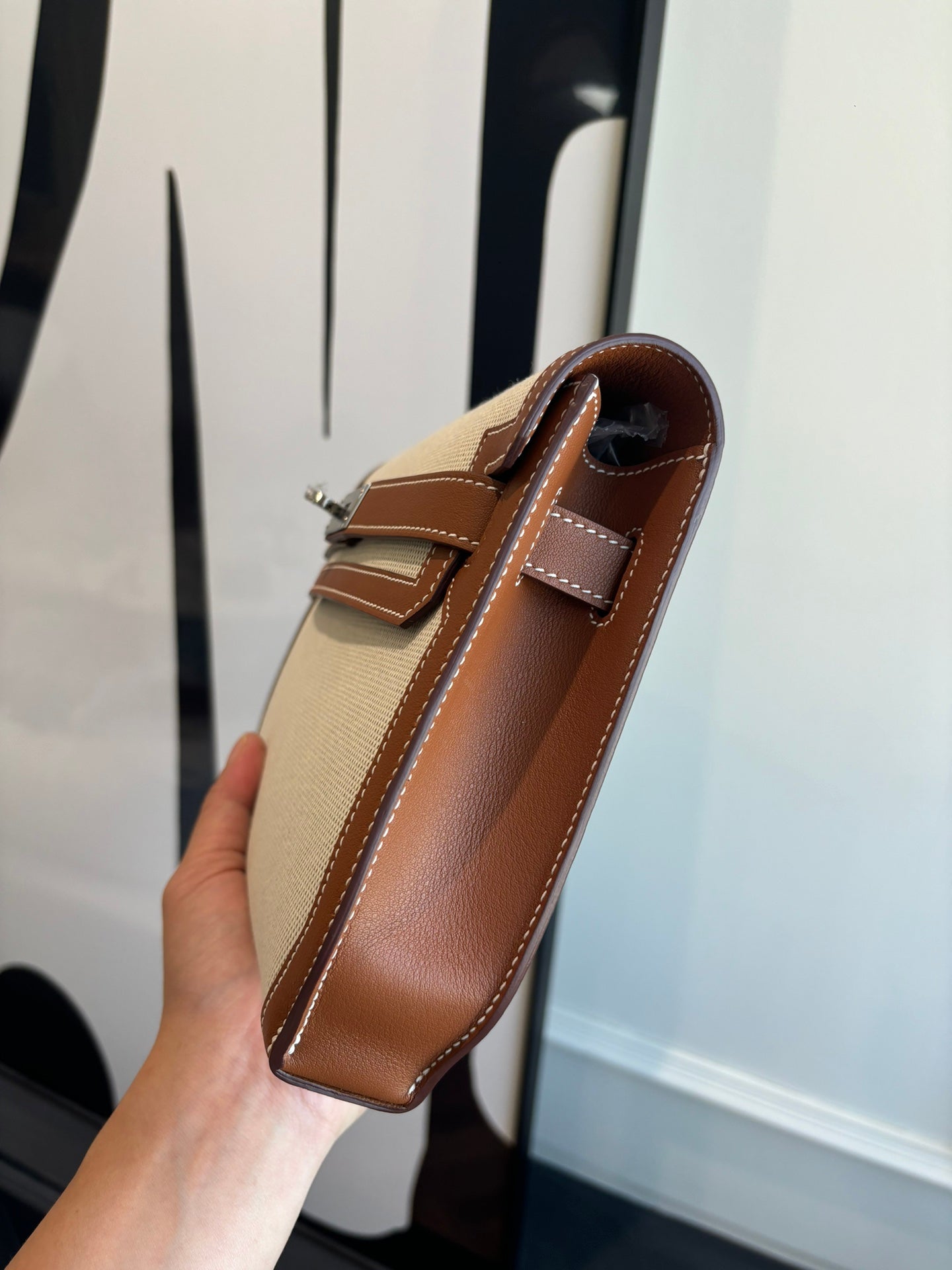 Hermes bag side view, light canvas with brown leather strap and top handle