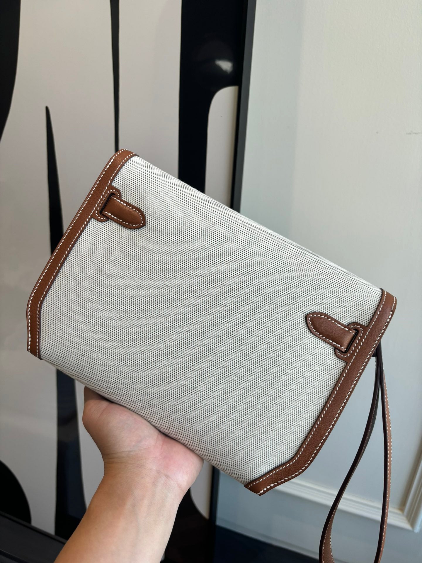 Hermes crossbody bag front view, light canvas body with brown leather flap and strap