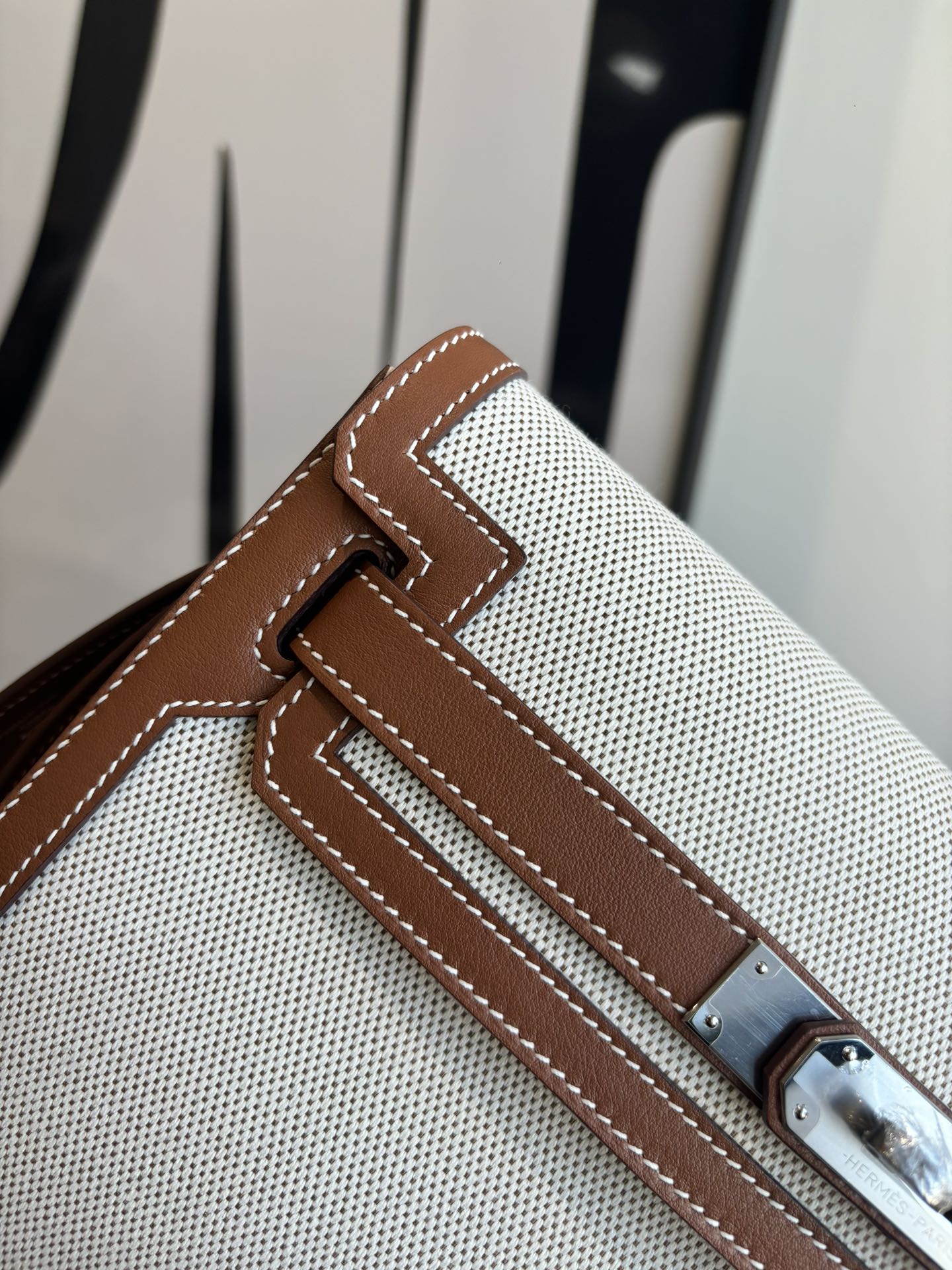 Hermes bag close-up, brown leather front panel with metal clasp and stitched detailing