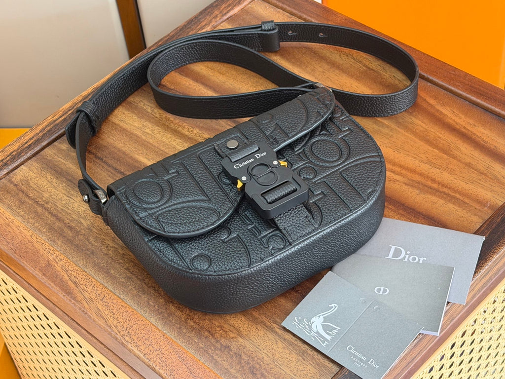 Dark crossbody bag with top handle and long strap, front buckle and flap