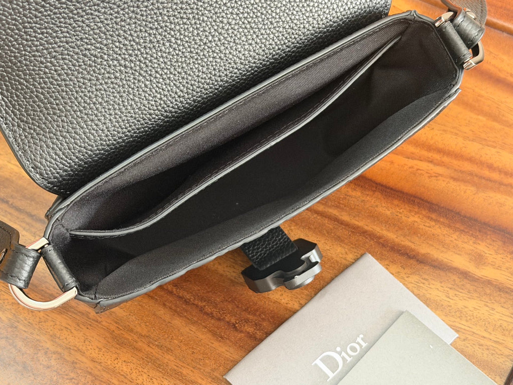 Crossbody bag open to show black interior with stitched edges and strap attachment