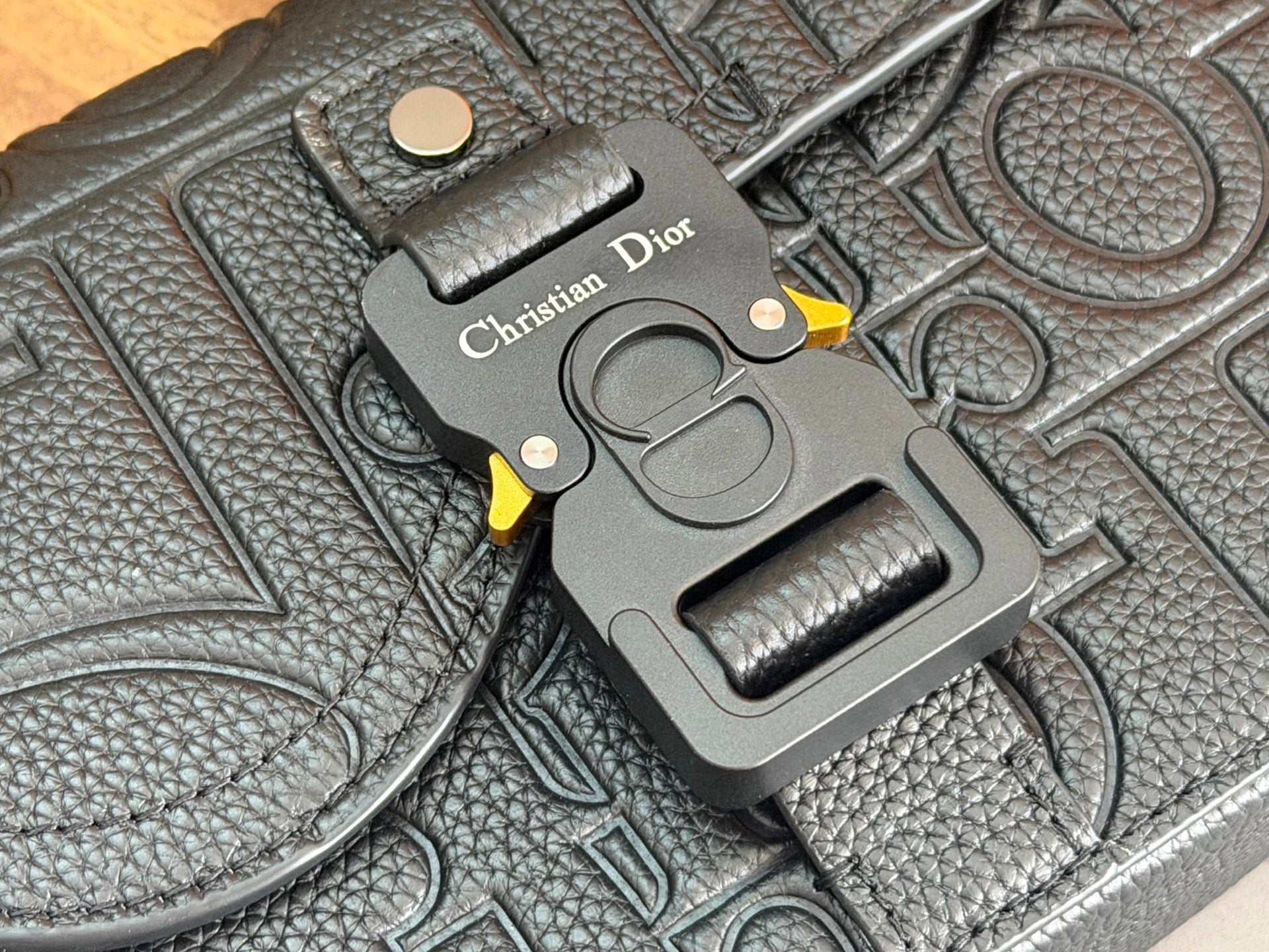 Embossed dark leather Dior bag corner with metal charm and 'Christian Dior' tag