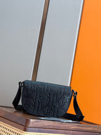 Navy embossed crossbody bag with front flap, gold-tone hardware, and shoulder strap